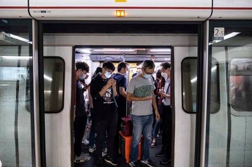 A subway station in Hong Kong, where crews wipe escalator handrails with disinfected rags.